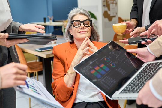 Stressed businesswoman meditating amidst chaos at the office