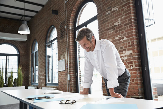 Smiling businessman looking at documents on desk