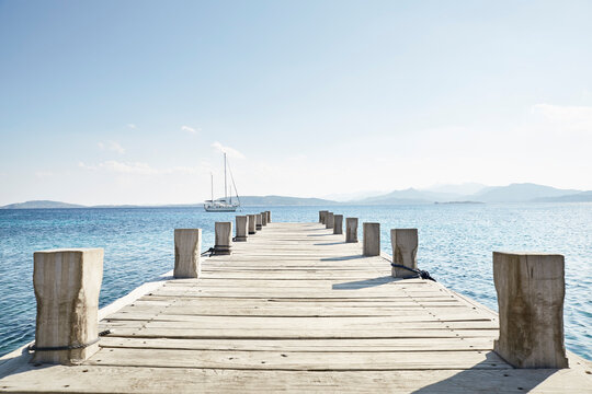 Empty jetty and saling boat in the background