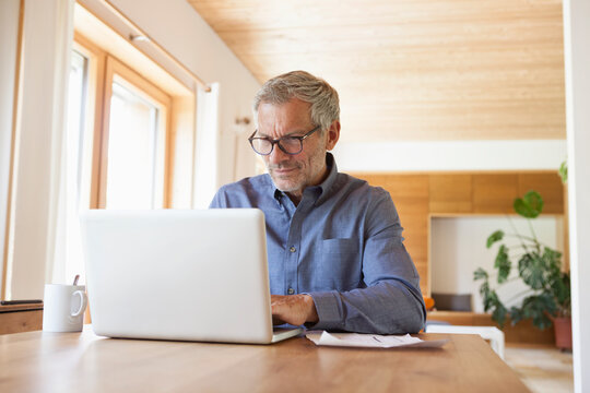 Mature man using laptop on table at home