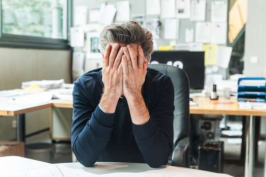 Mature man sitting in office with head in hands