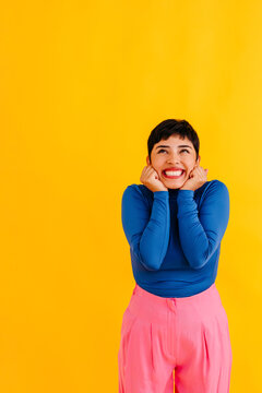 Excited woman with pixie cut against yellow background