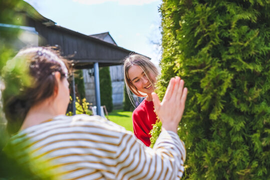 Neighbors greeting during backyard spring garden maintenance