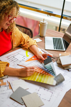 Interior designer analyzing blueprint and color swatch at desk