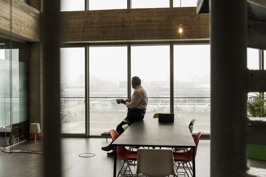 Senior manager in office holding cup of coffee, looking serious