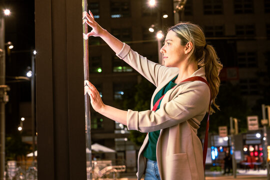 Woman using interactive digital display in city at night