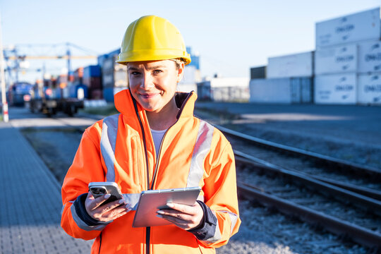 Logistics worker with tablet and smartphone at shipping yard