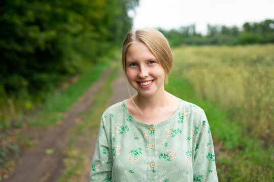Smiling woman in vintage dress outdoors by a summer wheat field