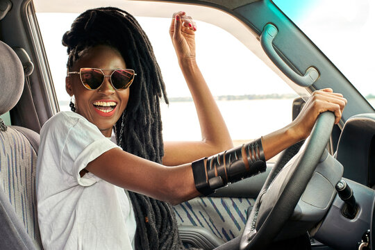 Portrait of laughing woman with dreadlocks driving car