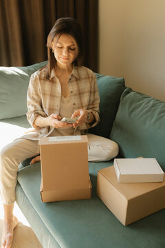 Customer using smartphone with delivery boxes on sofa