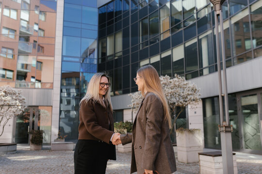 Businesswomen shaking hands outdoors finalizing corporate agreement