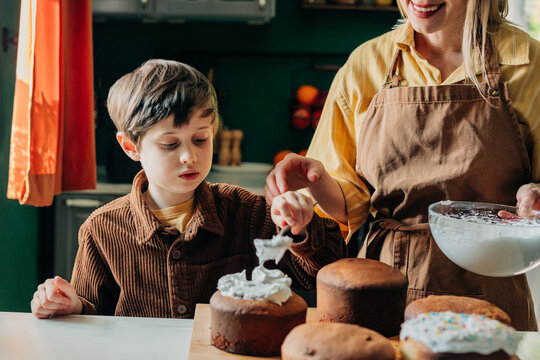 Mother and son decorating Easter bread with icing at home
