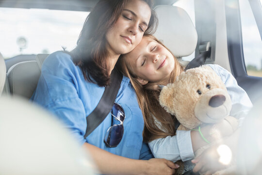 Mother and daughter on road trip sitting in car, sleeping