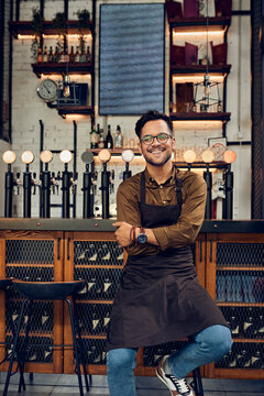 Portrait of a confident waiter at the counter in a pub