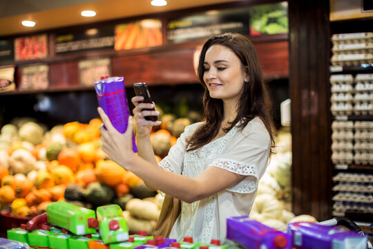 Woman at supermarket scanning prices with her smart phone