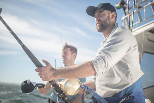 Two men fishing together at the stern of a boat
