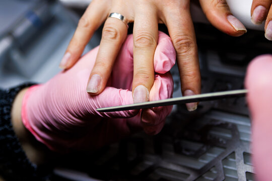 Manicurist shaping client nails with a file at a beauty salon for professional nail care
