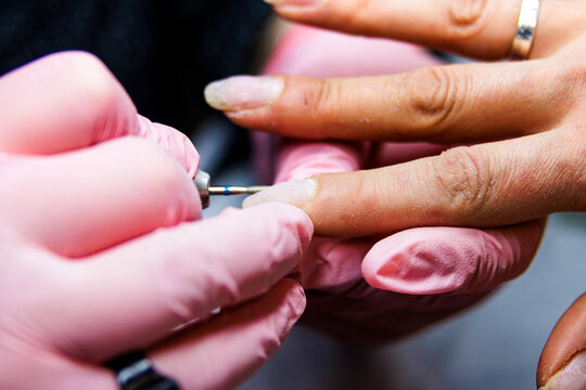 Manicurist working on client nails using an electric file in a beauty salon