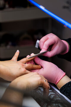 Manicurist working on client nails at beauty salon, shaping manicure, self care