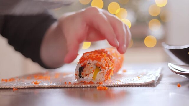 Professional chef slicing california sushi roll with sharp knife on bamboo mat.