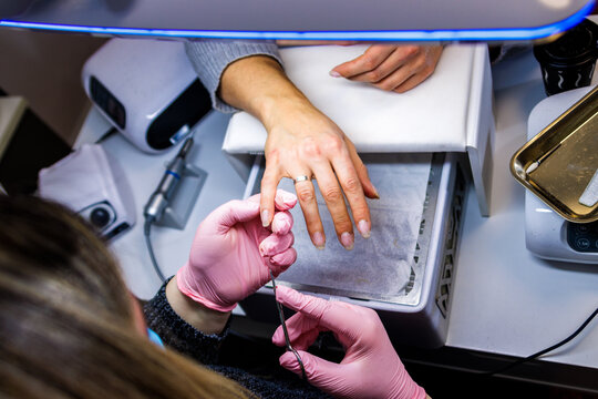 Manicurist applying professional nail care treatment to customer hand in beauty salon