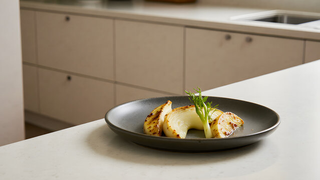 Minimalist kitchen detail with grilled food on black plate and clean cabinets