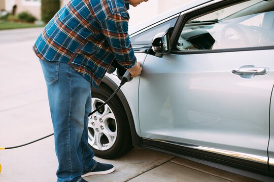 Man plugging hybrid electric car into home charging station