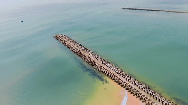 Aerial drone view of a tetrapod breakwater jetty with turquoise water