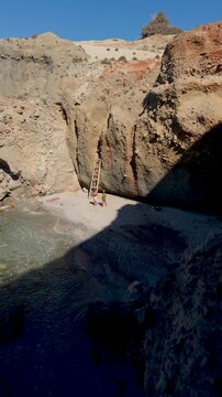 A couple discovers stunning hidden coves in Milos Greece where crystal-clear waters meet rugged cliffs. Perfect for a peaceful day of relaxation and adventure in the Cyclades, Tsigrado Beach