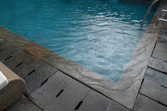 Blue swimming pool water ripples beside a light pool edge and tiled outdoor surface. Suitable for poolside, resort, leisure, swimming area