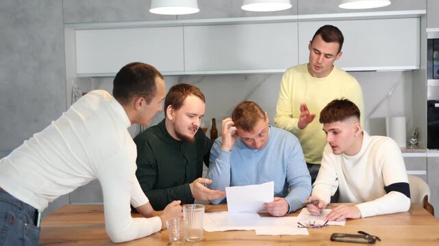 Friends reading financial documents and trying to solve problems together while sitting at table in their home kitchen