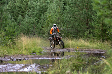 Naklejka premium Enduro racer in front of puddle of water during competition race
