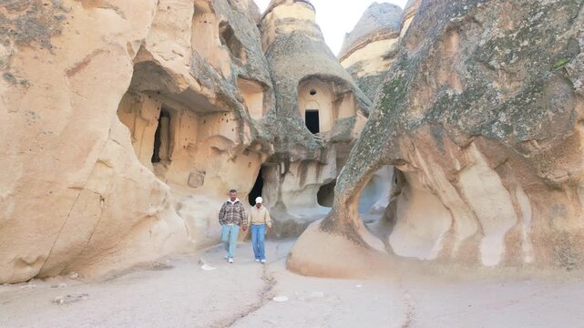 Witness the breathtaking landscape of Cappadocia, Turkey, where visitors admire stunning rock formations and fairy chimneys. Experience the rich history and beauty of this travel destination.