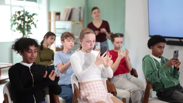 Teenage children scan the qr code on the presentation screen to get additional materials on the school curriculum. Schoolchildren using mobile phone in classroom. High quality 4k footage