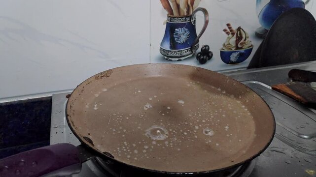 Closeup view of hot pan with water droplets sizzling before making dosa batter