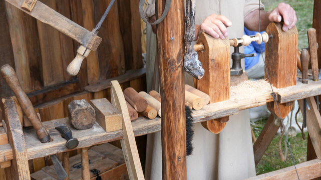 traditional craftsman using a wooden lathe at a medieval market stall