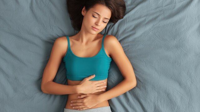 Woman experiencing abdominal pain lying in bed feeling sick from menstrual cramps or digestive issues