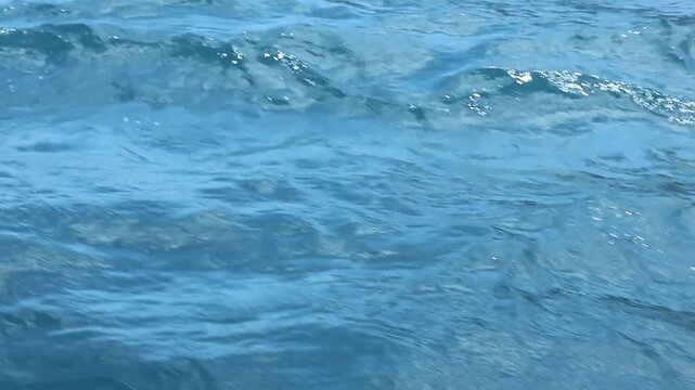 High-resolution clean background texture of ripples and small waves on a blue ocean water surface.