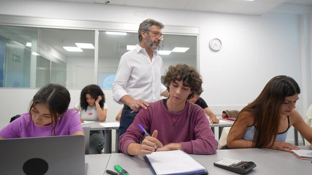 Diligent high school students working together and receiving guidance from their male professor during a lesson, fostering a collaborative and supportive learning environment in the classroom