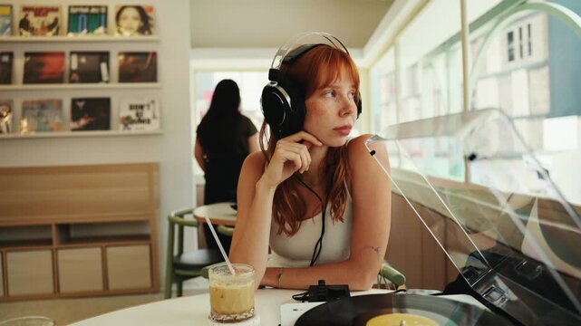 Young woman with headphones listening to vinyl record