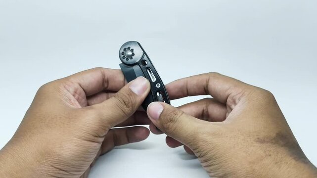 Hands Opening and Closing a Black Folding Knife on White Background