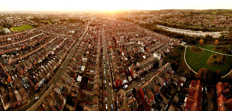 Aerial view of rows of terraced houses and suburban streets during sunset with a green park in the foreground in Exeter, England, United Kingdom.
