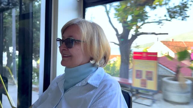 Senior Woman Riding Bus in Mediterranean City. Smiling senior woman traveling by public bus in a Mediterranean European city. Mature tourist enjoying active retirement and urban travel.