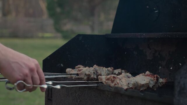 Fresh marinated meat grilling on metal skewers over hot charcoal and open flame
