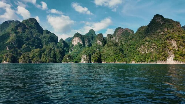 Khao sok national park lake view from boat in Thailand. Tracking shot of wooden boat bow gliding across mountain lake.