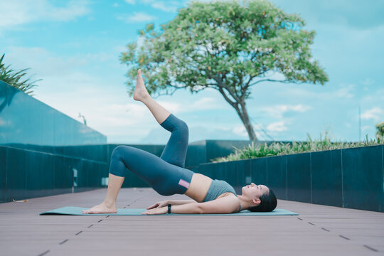 Young woman engaging in daily yoga exercise, practicing wellness and maintaining fitness outdoors on a mat, focusing on healthy lifestyle and mindful movement