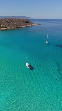 Bask in the beauty of Simos Beach on Elafonisos Island, where turquoise waters meet golden sands. Sailboats glide gracefully, inviting tranquil adventures under the sun.