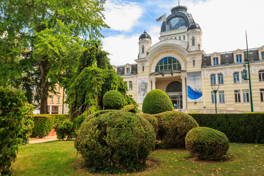 Beautiful front view of the historic Palais Lumiere building in Evian, France. Elegant Belle Epoque architecture with decorative manicured bushes and topiary in the foreground