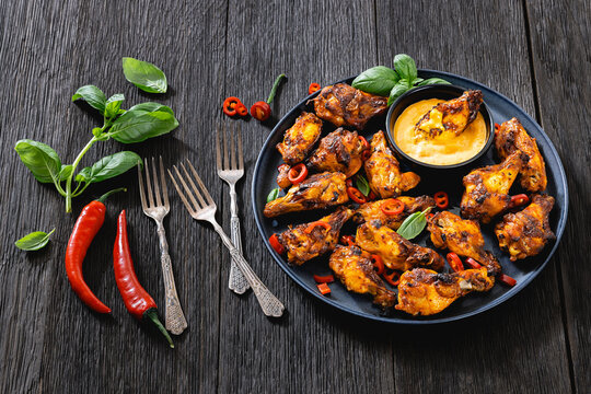 Char-grilled chicken wings on a plate with sauce