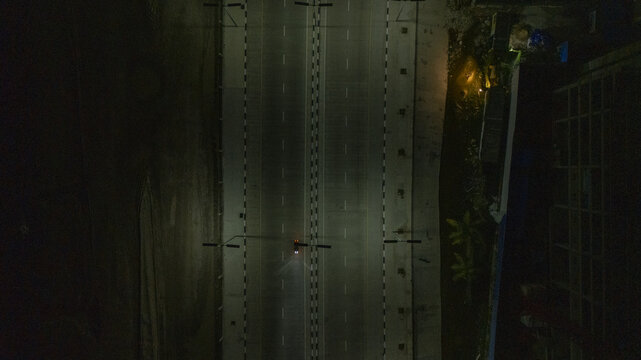 Aerial view of the Lagos-Calabar Coastal Road at night with streetlights illuminating the multi-lane highway and a single vehicle in Lekki, Lagos, Nigeria.